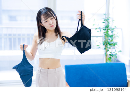 リビングで洋服と下着を選ぶ若い女性 スポーツブラ 下着選び リビングで洋服と下着を選ぶ若い女性 スポーツブラ 下着選び 121098164