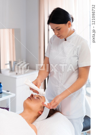 Masseuse taking cream in hand from bottle while Masseuse taking cream in hand from bottle while 121098732