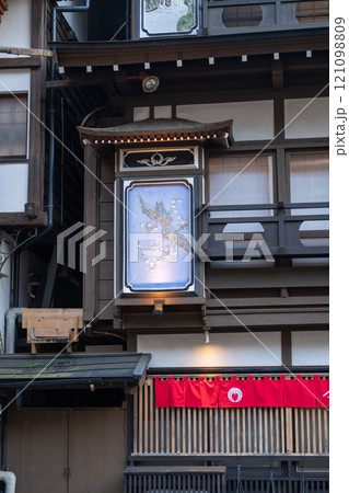 Ginzan onsen, Yamagata, Japan ,Traditional building with a decorative sign and red fabric banner. Ginzan onsen, Yamagata, Japan ,Traditional building with a decorative sign and red fabric banner. 121098809