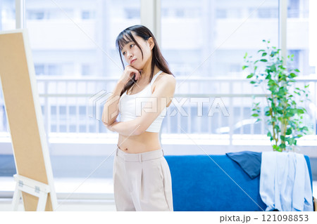姿見鏡の前で洋服と下着選びを迷う若い女性　スポーツブラ　下着選び　 121098853