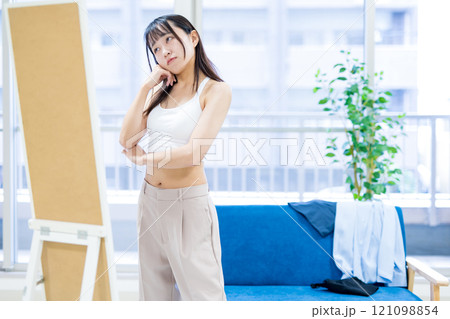 姿見鏡の前で洋服と下着選びを迷う若い女性　スポーツブラ　下着選び　 121098854