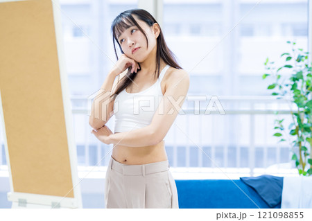 姿見鏡の前で洋服と下着選びを迷う若い女性　スポーツブラ　下着選び　トリミングアップ 121098855