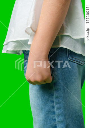 A child stands in front of a bright green background close up 121100134