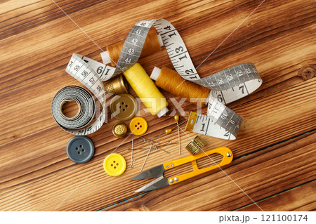 Crafting tools and materials arranged on a wooden table for sewing projects Crafting tools and materials arranged on a wooden table for sewing projects 121100174