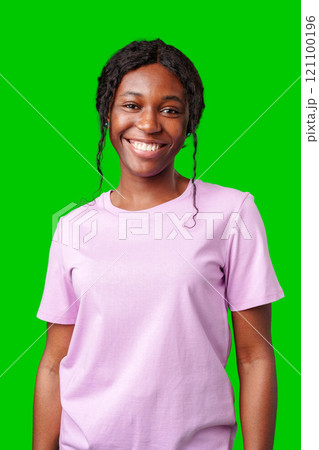 Young woman smiling joyfully in a pink shirt against a vibrant green background in a cheerful atmosphere 121100196