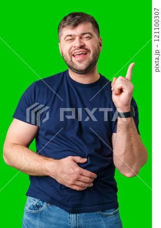 A man with a friendly smile gestures upwards while wearing a navy shirt against a bright green background 121100307