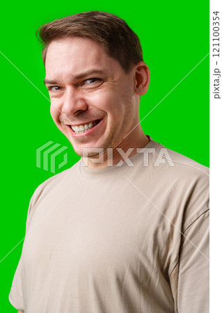 Smiling man in a beige shirt poses against a bright green background 121100354
