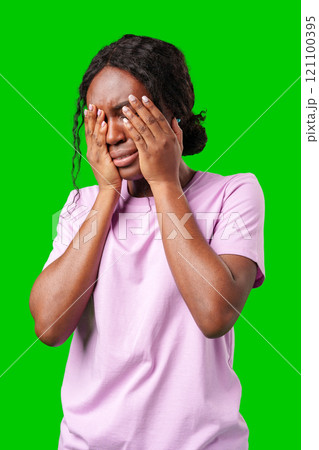 Woman expressing frustration while standing against a bright green background Woman expressing frustration while standing against a bright green background 121100395