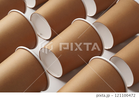 A collection of disposable paper cups arranged in a repeating pattern on a light background A collection of disposable paper cups arranged in a repeating pattern on a light background 121100472