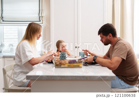 A family is eating a meal together at their kitchen table A family is eating a meal together at their kitchen table 121100638