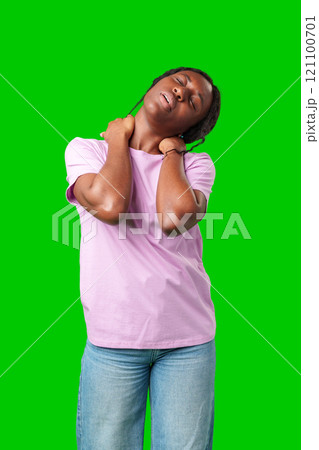 Young woman experiencing neck pain against a bright green background 121100701