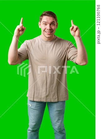 Enthusiastic man pointing upwards against a vibrant green background Enthusiastic man pointing upwards against a vibrant green background 121100768
