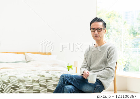 ベッドルームでコーヒーを飲むミドル男性 121100867