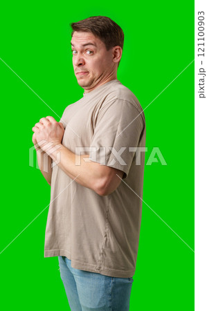 Young man making a disgusted expression while standing against a bright green background 121100903