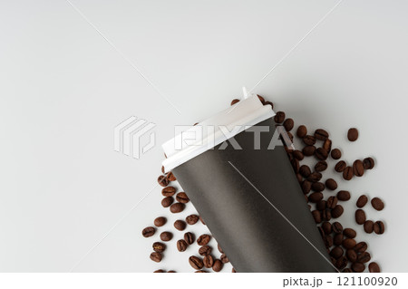 A paper coffee cup surrounded by freshly roasted coffee beans on a clean white background A paper coffee cup surrounded by freshly roasted coffee beans on a clean white background 121100920