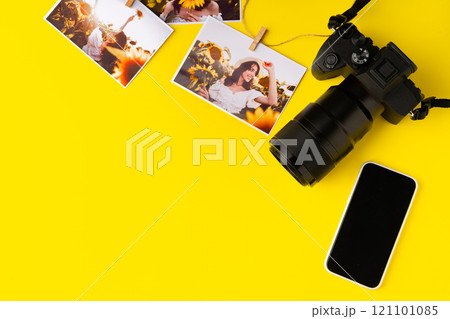 Photo camera with colorful printer photos on yellow background Photo camera with colorful printer photos on yellow background 121101085