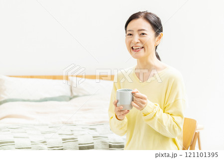 ベッドでコーヒーを飲むミドル女性 121101395