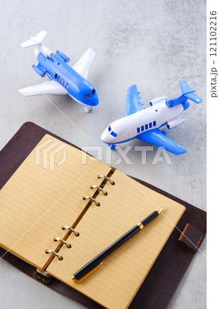 飛行機と、開いたリング式のシステム手帳で、次の長期休暇に旅行を計画しているイメージ 121102216