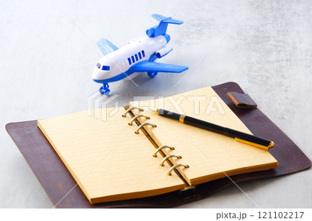 飛行機と、開いたリング式のシステム手帳で、次の長期休暇に旅行を計画しているイメージ 飛行機と、開いたリング式のシステム手帳で、次の長期休暇に旅行を計画しているイメージ 121102217