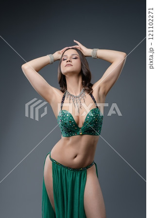 Belly dancer performing with grace and elegance in a vivid green costume 121102271