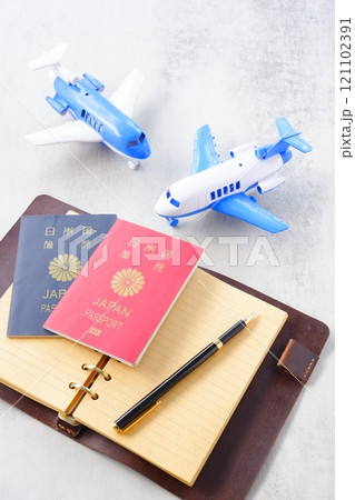 パスポート(10年用赤色と5年用紺色)と飛行機、開いた手帳で、海外旅行を計画しているイメージ パスポート(10年用赤色と5年用紺色)と飛行機、開いた手帳で、海外旅行を計画しているイメージ 121102391
