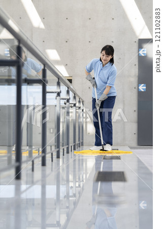 ビル清掃イメージ　フロアのモップかけをするミドルの女性清掃スタッフ 121102883