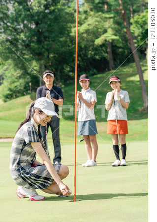 ゴルフ場のグリーンでゴルフをするゴルファーの男女(パター) 121103010