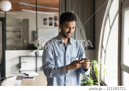 Man using cellphone at workplace, checking messages, responding to emails 121103721