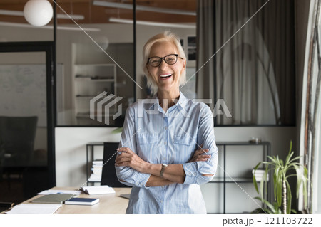 Successful businesswoman standing with arms crossed, laughing, posing for camera 121103722