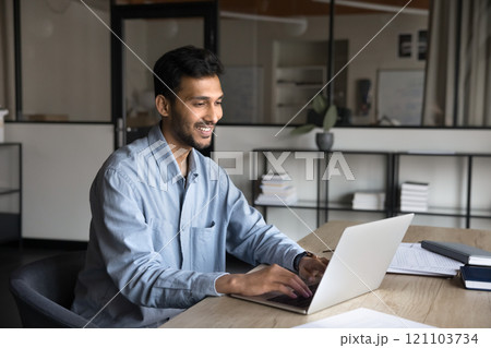 Indian man using laptop at modern workplace Indian man using laptop at modern workplace 121103734
