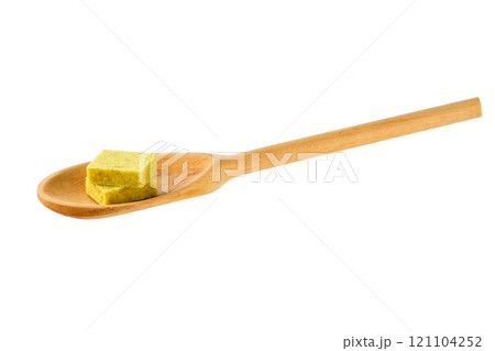 Bouillon cube in a wooden spoon isolated on a white background. Bouillon cube in a wooden spoon isolated on a white background. 121104252