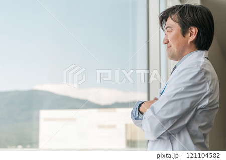 窓の外を眺める白衣姿の中年男性医師・医者・ドクター・お医者さん・医療従事者 121104582