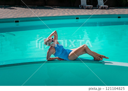 Bikini-clad woman enjoys poolside relaxation. Poolside ambiance. Capturing woman's relaxed time near pool. 121104825