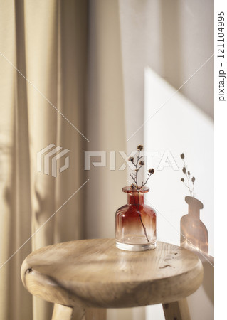 Warm sunlight streaming in through the window, beige background, flowers, vases, and a table with plants. Harmony of light and shadow. 121104995
