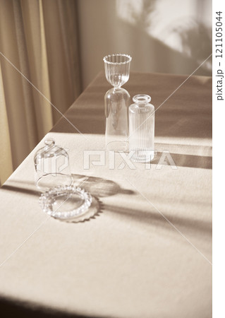 Warm sunlight streaming in through the window, beige background, flowers, vases, and a table with plants. Harmony of light and shadow. Warm sunlight streaming in through the window, beige background, flowers, vases, and a table with plants. Harmony of light and shadow. 121105044