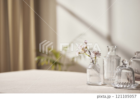 Warm sunlight streaming in through the window, beige background, flowers, vases, and a table with plants. Harmony of light and shadow. 121105057