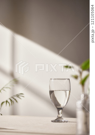 Warm sunlight streaming in through the window, beige background, flowers, vases, and a table with plants. Harmony of light and shadow. 121105064