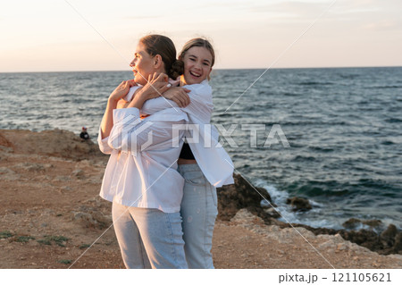 Mother Daughter Beach Sunset - Happy mother and daughter embracing at sunset on a beach. 121105621