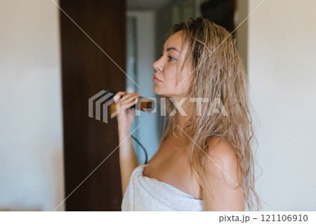 Young woman drying her hair with a styler, a hair dryer at home 121106910
