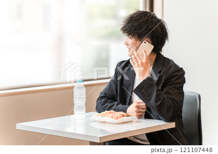 食堂・カフェでランチを食べながらスマホで電話するビジネスマン・男性 食堂・カフェでランチを食べながらスマホで電話するビジネスマン・男性 121107448