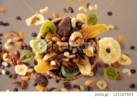 Dried tropical fruits with various nuts and raisins on a beige background. Dried tropical fruits with various nuts and raisins on a beige background. 121107605