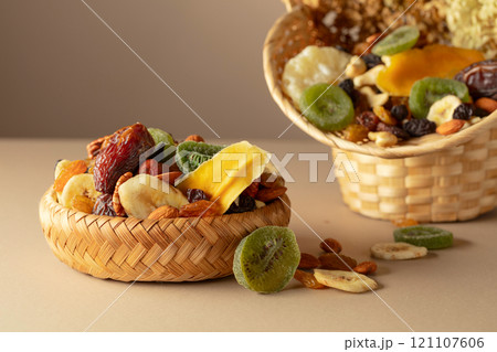 Dried tropical fruits, nuts and raisins on a beige background. 121107606