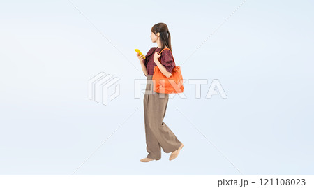スマホを持って歩くカジュアルウェアの女性の全身写真 スマホを持って歩くカジュアルウェアの女性の全身写真 121108023
