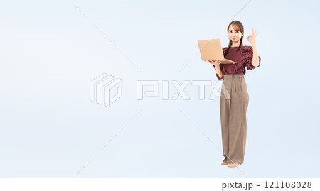 PCを持ってOKサインを見せるカジュアルウェアの女性の全身写真 PCを持ってOKサインを見せるカジュアルウェアの女性の全身写真 121108028