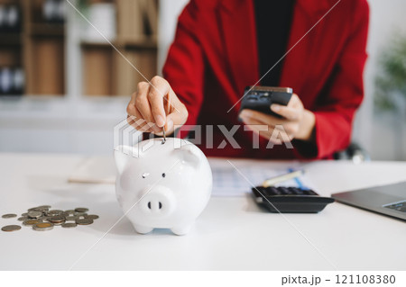 Women are putting coins in a piggy bank for a business that grows for profit and saving money for the future. Women are putting coins in a piggy bank for a business that grows for profit and saving money for the future. 121108380