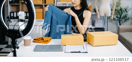 Fashion blogger concept, Young Asian women selling clothes on video streaming.Startup small business SME, using smartphone or tablet taking receive and checking Fashion blogger concept, Young Asian women selling clothes on video streaming.Startup small business SME, using smartphone or tablet taking receive and checking 121108517