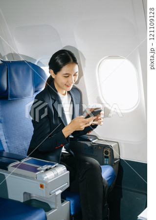 Young Asian executive excels in first class, multitasking with digital tablet, laptop and smartphone. Young Asian executive excels in first class, multitasking with digital tablet, laptop and smartphone. 121109128