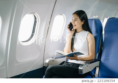 Attractive Asian female passenger of airplane sitting in comfortable seat while working laptop and tablet with mock up area using wireless connection. Travel in style, work 121109154
