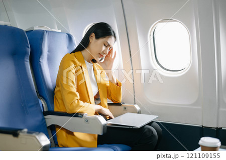 Photo of a frustrated woman sitting on an airplane with her head in her hands. Asian woman sitting in a seat Photo of a frustrated woman sitting on an airplane with her head in her hands. Asian woman sitting in a seat 121109155