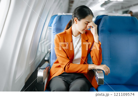 Photo of a frustrated woman sitting on an airplane with her head in her hands. Asian woman sitting Photo of a frustrated woman sitting on an airplane with her head in her hands. Asian woman sitting 121109574